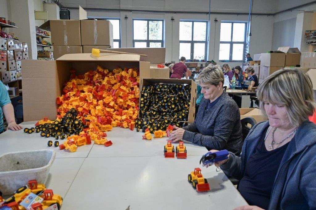 Dvě zaměstnankyně s krabicemi plnými hraček skládají malé bagry